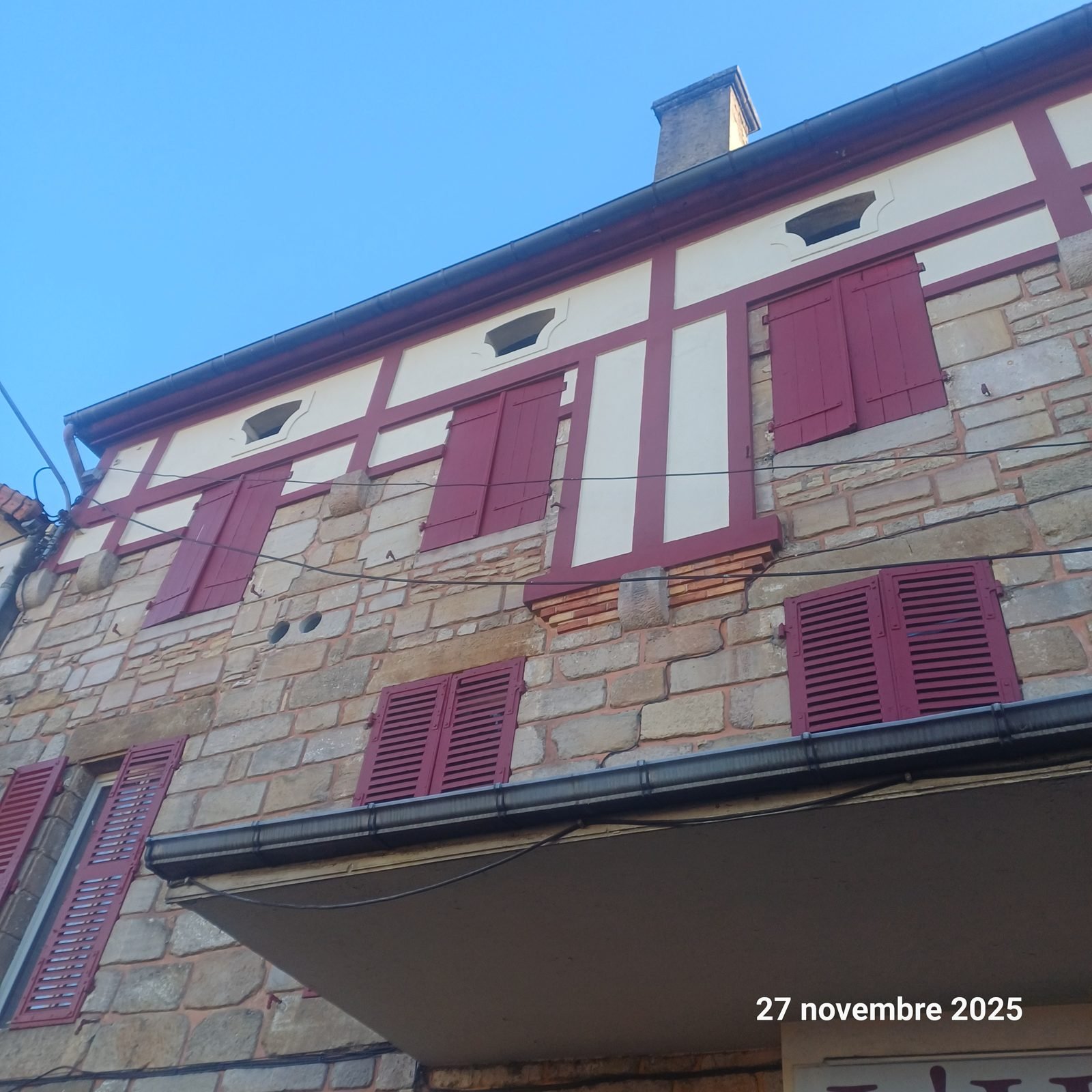 Maison en pierre avec volets bordeaux repeints